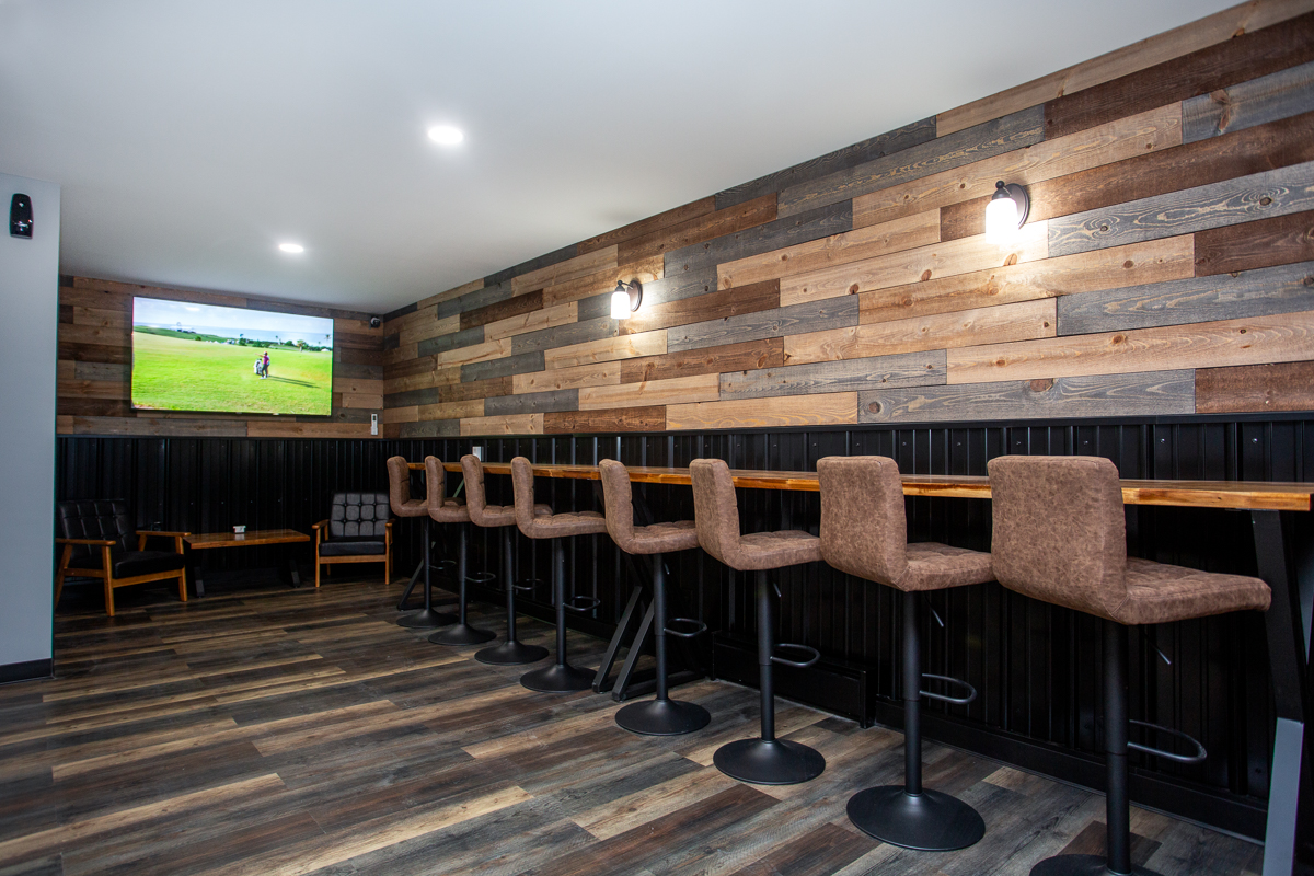 Lounge bar with wood plank walls and brown upholstered stools at HD Sports Zone