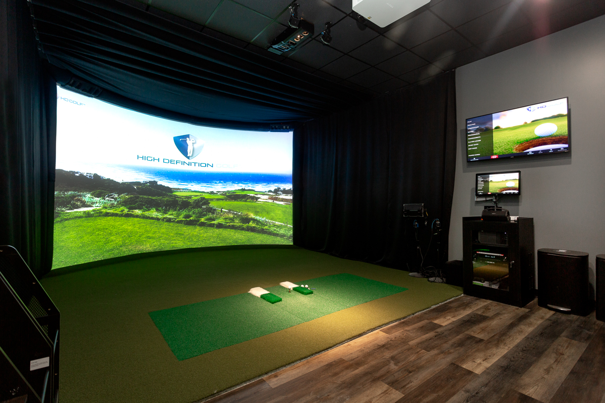 Empty HD Golf simulator bay with panoramic HIGH DEFINITION GOLF screen at HD Sports Zone